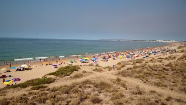 Повітряна фотографія узбережжя, дюн, пляжів Гейла в Португалії. Туристи плавають в океані й відпочивають на підлозі парасолями.. — стокове відео