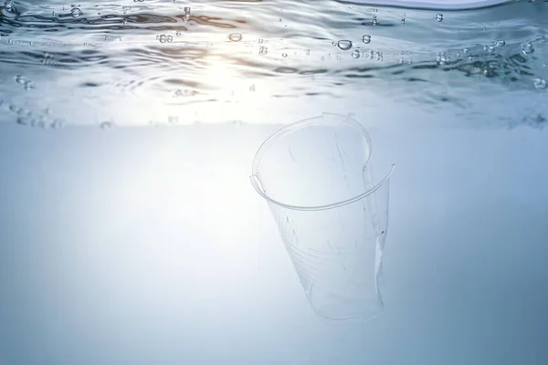 A globális környezeti probléma, a környezetszennyezés, a tengerek és folyók hulladékai. Műanyag pohár víz alatt. — Stock Fotó