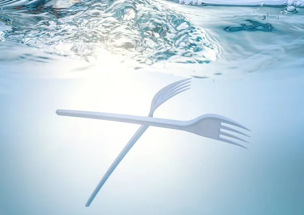 The global ecological problem, environmental pollution, waste in the seas and rivers. Plastic fork under water.