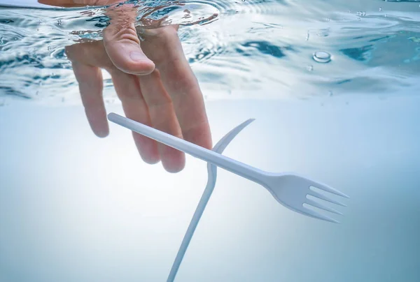 El problema ecológico de la contaminación del agua, el medio ambiente. Mano sacando tenedores de plástico . — Foto de Stock