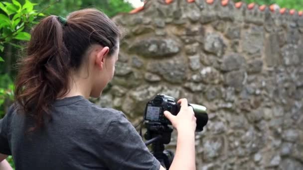 Egy fiatal lány, egy fotós, egy erdős területen, képeket készít a gyönyörű természetről. Közelkép. — Stock videók