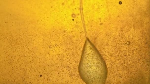Combustible, amarillo, aceite dorado vertido en un recipiente de vidrio en el laboratorio, distribuyendo las burbujas, soplando un chorro . — Vídeo de stock