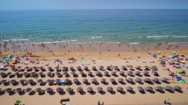 海岸の空中写真、ポルトガルのゲールのビーチ。傘の下でリラックスして海で泳ぐ. — ストック動画