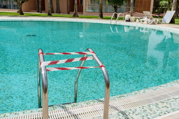 La piscina durante el coronavirus, situada en el territorio del hotel, envuelta en una cinta que prohíbe la entrada en ella . —  Fotos de Stock