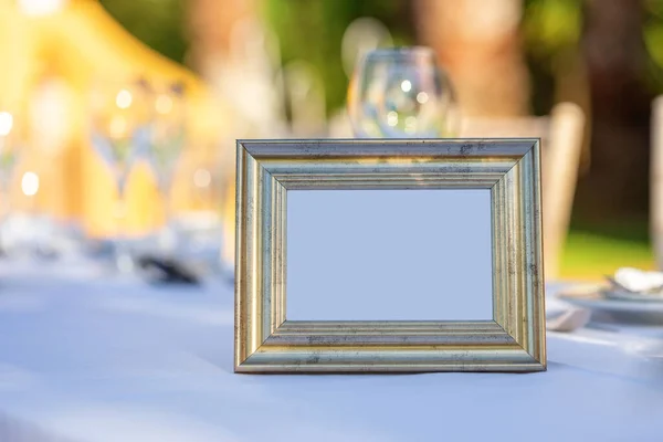 Starožitný pozlacený rám na fotografii, stojící na stole se sklenicí a nádobím. Kopírovat prostor. — Stock fotografie