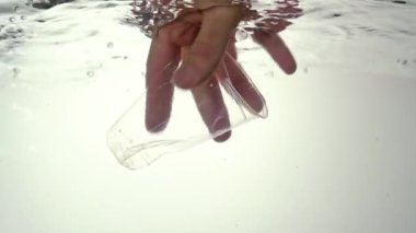 Okyanusların, denizlerin ve nehirlerin küresel çevre kirliliği sorunu. Bir erkek eli suya plastik bir bardak atar. Yakın plan..