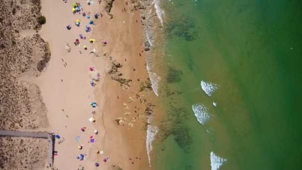 海岸の空中写真、ポルトガルのゲールのビーチ。観光客は傘の下で休み、透明度の高いターコイズブルーのサンゴ礁で泳ぐ. — ストック動画