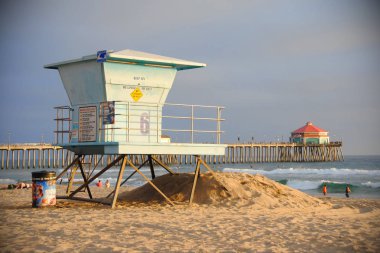 Huntington Beach, California/Amerika Birleşik Devletleri - 26 Ocak 2015: Bir cankurtaran Kulesi bir Kaliforniya sahilde gün batımında. Huntington Beach iskelesinden çok geride olduğunu. 
