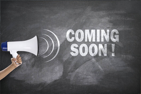 Megaphone with coming soon sign on blackboard