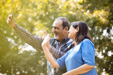 Video görüşmesi için cep telefonu kullanan mutlu yaşlı çift.