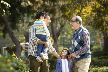 Parktaki mutlu çoklu nesil Hint ailesi.