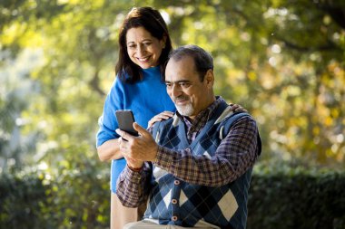 Üst düzey kadın cep telefonu kullanarak kocasıyla medya içeriğini paylaşıyor