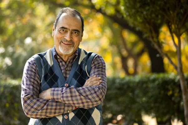 Homem idoso confiante com braços cruzados no parque — Fotografia de Stock