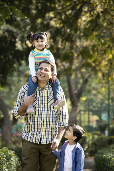 Pai carregando filha nos ombros e segurando as mãos de seu filho no parque — Fotografia de Stock