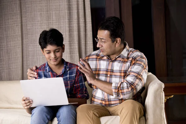 Pai e filho espantados ao receber boas notícias usando laptop — Fotografia de Stock