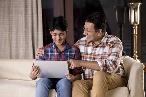 Pai e filho espantados ao receber boas notícias usando laptop — Fotografia de Stock