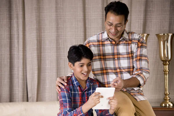 Pai e filho surpreendidos ao receber boas notícias usando tablet digital — Fotografia de Stock