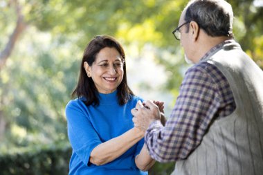 Parkta el ele tutuşan mutlu yaşlı çift.