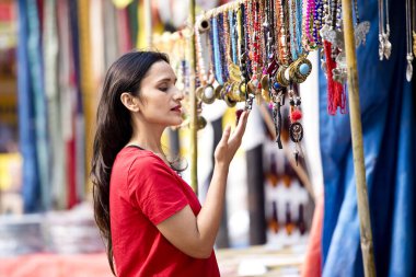 Two women shopping for necklace and earrings at street market