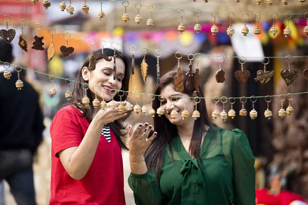 Two women shopping for necklace and earrings at street market — Stockfoto