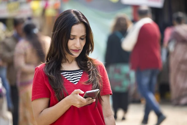 Mujer feliz mensajes de texto en el teléfono móvil en el mercado — Foto de Stock