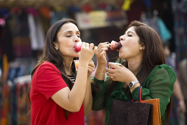 Дві жінки їдять ароматизований лід, занурений у сироп — стокове фото