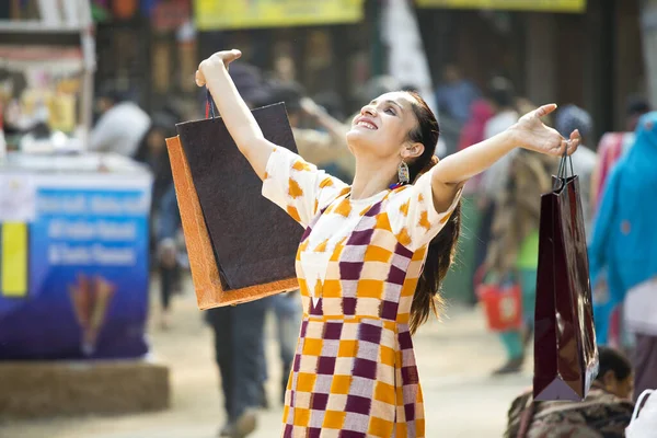 Excited woman holding shopping bags at street market — Stockfoto