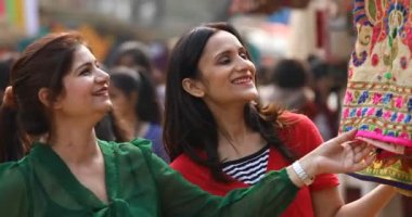 Two women shopping for dress at street market
