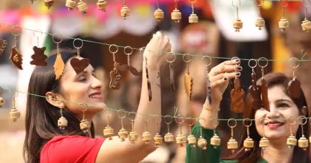 Two women shopping for necklace and earrings at street market — ストック動画