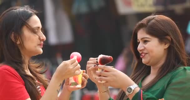 Две женщины едят ароматизированную голу со льдом, смоченную в сиропе — стоковое видео