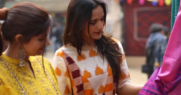 Two women shopping for dress at street market — Stockvideo