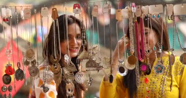 Two women shopping for necklace and earrings at street market — Stok video