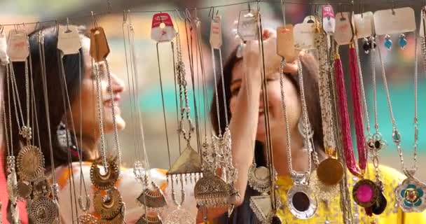 Two women shopping for necklace and earrings at street market — Αρχείο Βίντεο