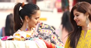 Two women shopping for dress at street market