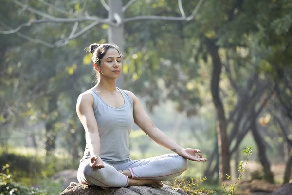 Park 'ta lotus pozisyonunda yoga yapan bir kadın.