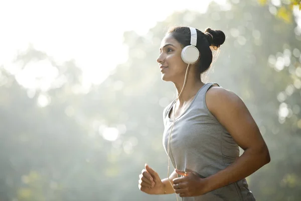 Deportiva escuchando música y trotando en el parque — Foto de Stock