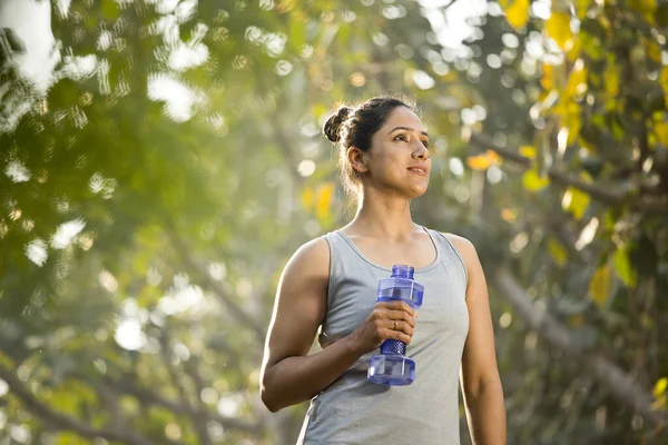 Fit mujer con forma de mancuerna botella de agua en el parque — Foto de Stock