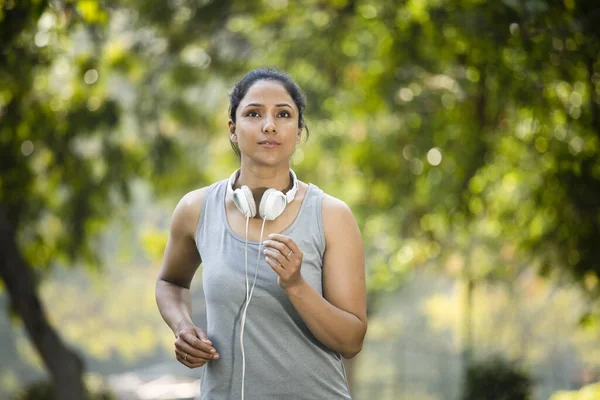 Deportiva escuchando música y trotando en el parque — Foto de Stock