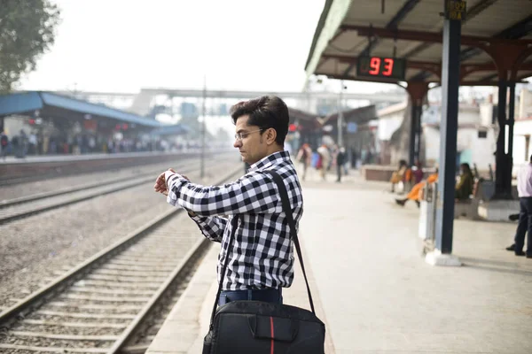 Hombre comprobando el tiempo mientras espera en la estación de tren — Foto de Stock