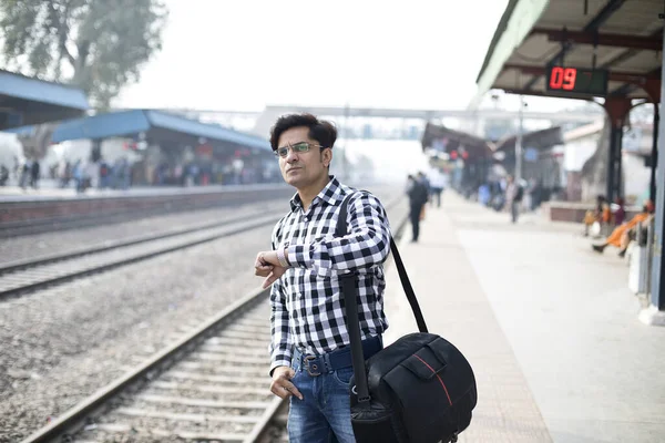 Hombre comprobando el tiempo mientras espera en la estación de tren — Foto de Stock