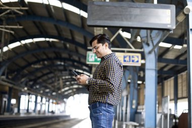 Tren istasyonunda cep telefonu kullanan bir adam.