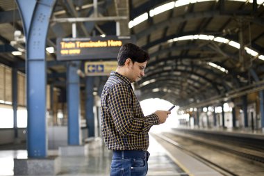 Tren istasyonunda cep telefonu kullanan bir adam.