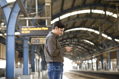 Tren istasyonunda cep telefonu kullanan bir adam.