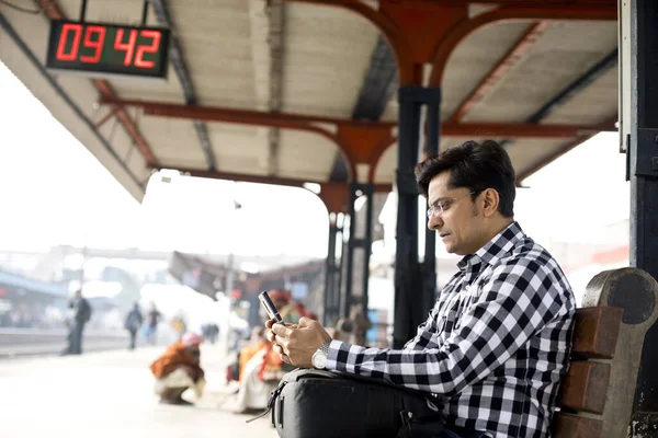 Hombre usando el teléfono mientras espera en la plataforma de la estación de tren — Foto de Stock