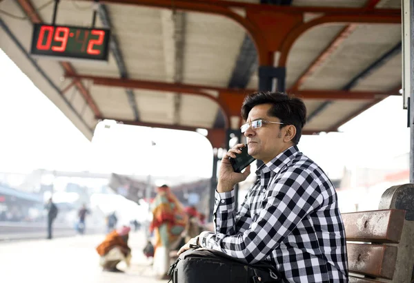 Homem usando telefone enquanto espera na plataforma da estação ferroviária — Fotografia de Stock