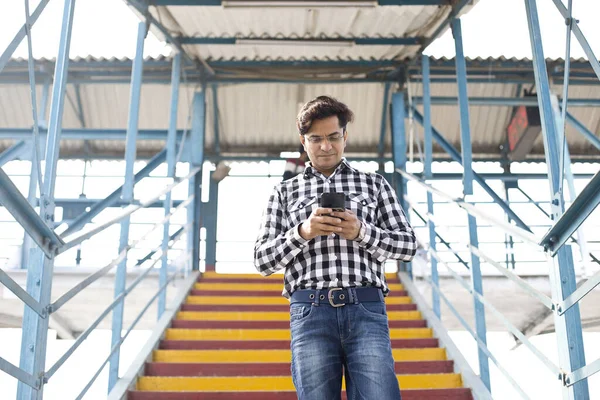 Hombre joven usando el teléfono móvil mientras camina por las escaleras — Foto de Stock