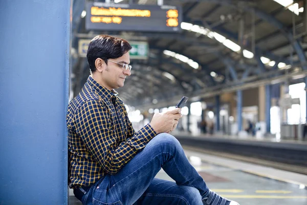 Hombre usando teléfono móvil en la plataforma de la estación de ferrocarril — Foto de Stock
