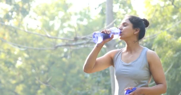 Mujer en ropa deportiva bebiendo agua en el parque — Vídeos de Stock