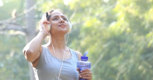 Fit woman with water bottle and headphones — Stock Video
