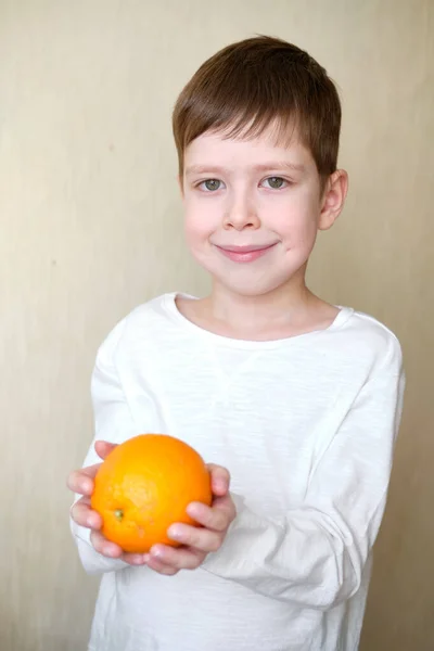 happy smiling boy with vitamin C and orange in hands